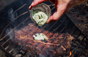 Chuck Steak on the grill with garlic parsley steak butter poured over top.