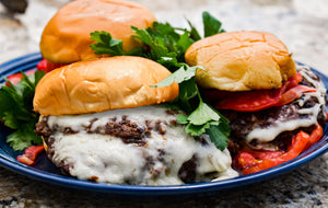 Plated steak burger with a melted provel cheese skirt.